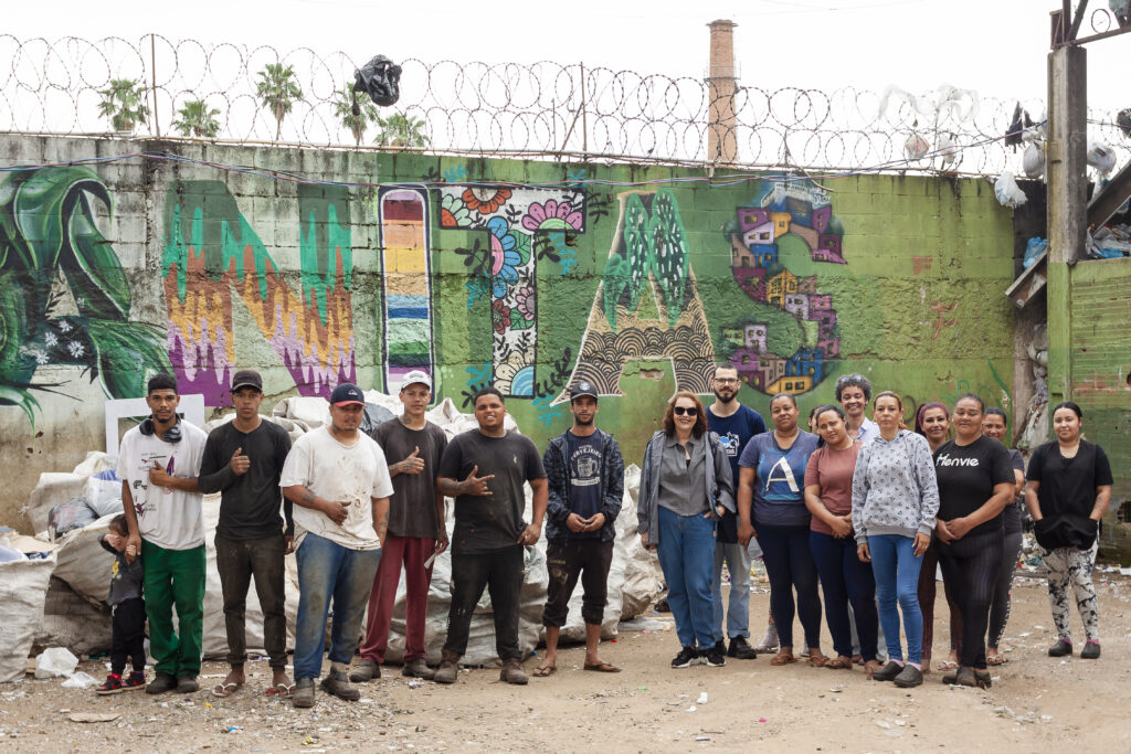 Catadoras e catadores da Cooperativa Anitas reunidos em frente a um graffiti escrito "Anitas"